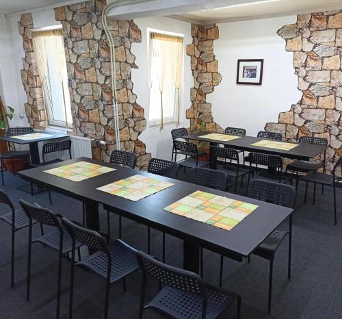 a room with tables and chairs in front of a stone wall at Abturist penzion in Štúrovo