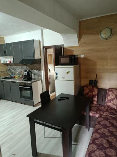 eine Küche mit einem schwarzen Tisch und einem Kühlschrank in der Unterkunft Апартамент за гости Централ in Malko Tŭrnovo