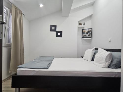 Un dormitorio con una cama con sábanas y almohadas blancas. en Apartment Roko, en Razvala