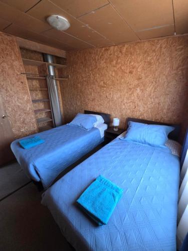 two beds in a room with blue sheets at Departamento los Villarroel 1 in Ancud