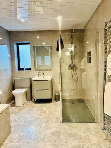 a bathroom with a shower and a toilet and a sink at Lewis Living in Aird Tong