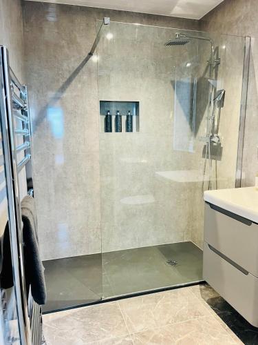a shower with a glass door in a bathroom at Lewis Living in Aird Tong