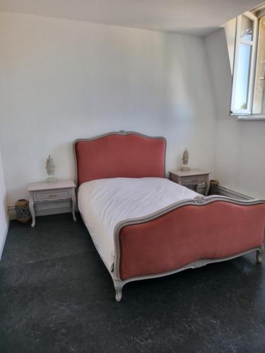 a red bed in a room with two tables at Hôtel De Ligny in Abbeville