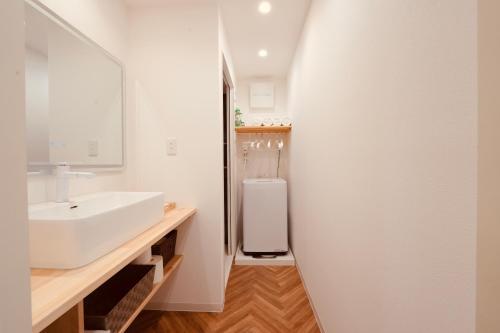 a white bathroom with a sink and a toilet at 雪山民宿 YUKI YAMA Hotel in Osaka