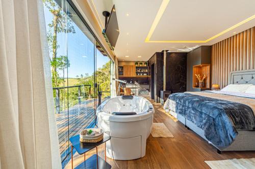 a bedroom with a tub and a bed and a balcony at Rancho Carolina Cabana Panther in Rancho Queimado