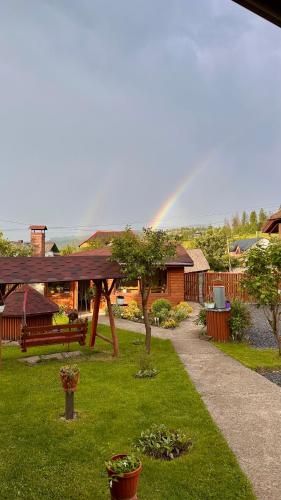 a rainbow in the distance with a garden with a bench at Три-О Апартаменти з видом на гори, максимум для 4 гостей, 15 хв від центру in Slavske