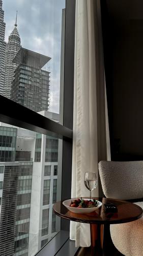 a table with a plate of food and a glass of wine at Premier Suites Twin Towers at Star Residences in Kuala Lumpur