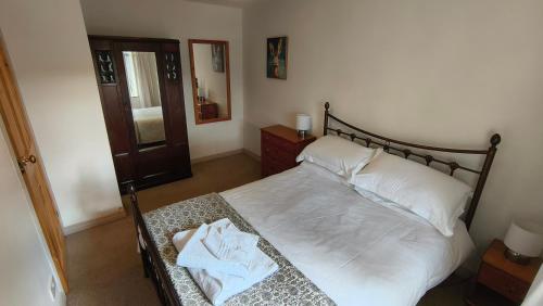 une chambre avec un lit avec des draps blancs et des oreillers dans l'établissement Mews Cottage, à Middleton in Teesdale