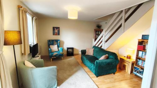 a living room with a green couch and a chair at Mews Cottage in Middleton in Teesdale