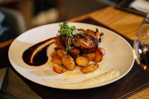 a plate of food with potatoes and meat on a table at Aparthotel Vucko in Jahorina