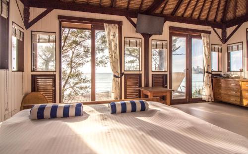 a bedroom with a bed with a view of the ocean at Barefoot Luxury at the Tip of Borneo in Kudat
