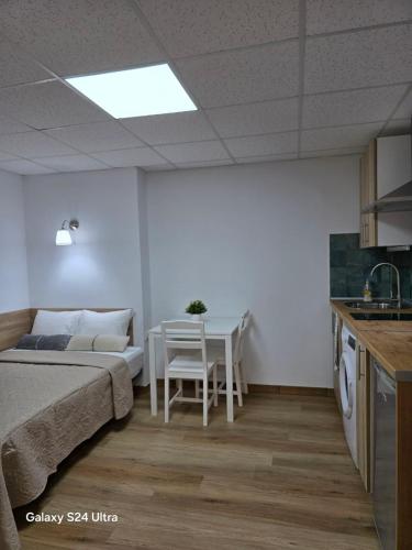 a bedroom with a bed and a table and a kitchen at BEACH Arguineguin FIRST LINE 8 studio CHG FAMILY HOTEL in Arguineguín