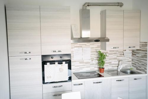 a kitchen with white cabinets and a sink at Casa Cleo al Mare con Free WiFi Netflix AC in Carrao