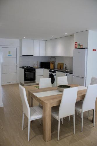 a kitchen with a wooden table and white chairs at Cantinho do Avô Almeida in Nazaré