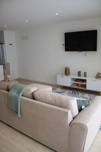 a living room with a couch and a flat screen tv at Cantinho do Avô Almeida in Nazaré