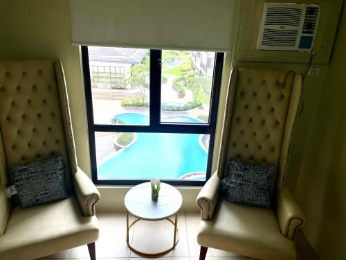 two chairs and a table in a room with a window at Relaxing Escape lovely STUDIO unit with a pool in Tagaytay