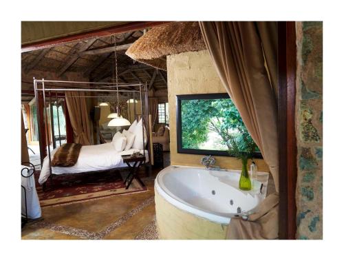 a bathroom with a tub and a bedroom with a bed at Lethabo Estate in Lanseria