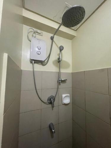 a shower in a bathroom with a shower head at Relaxing Escape lovely STUDIO unit with a pool in Tagaytay