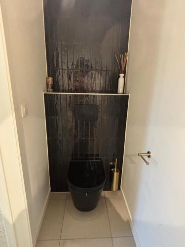 a bathroom with a toilet with a black tiled wall at Home Terboekt in Genk
