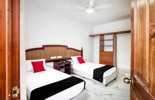 a bedroom with two beds with red pillows at Hotel Yukon in Playa del Carmen