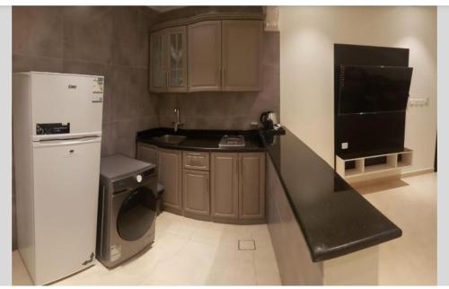 a small kitchen with a refrigerator and a dishwasher at شقة فندقية فاخرة in Taif