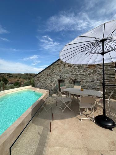 a patio with a table and an umbrella next to a swimming pool at Casa da Miquinhas in Murça