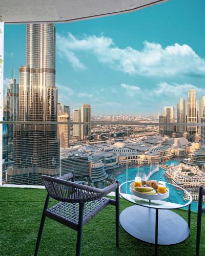 a balcony with a table and chairs and a view of a city at Stay in the #1 Burj & Fountain View 4BR Apartment in Dubai