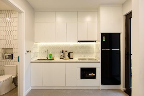 a kitchen with white cabinets and a black refrigerator at Nagomi Apartment in Hanoi
