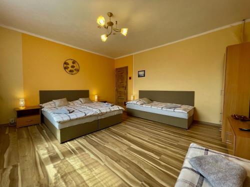 two beds in a room with yellow walls and wooden floors at One Floor under High Tatras in Malý Slavkov