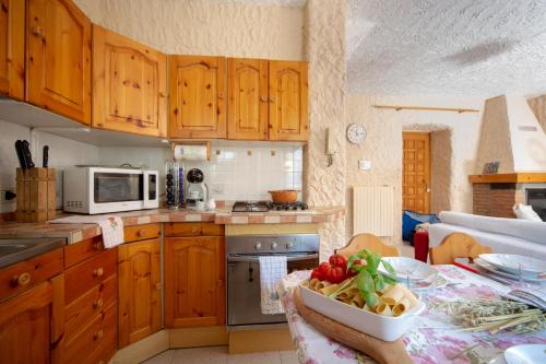 a kitchen with wooden cabinets and a table with a bowl of vegetables at 123 la casa nel bosco in Curino