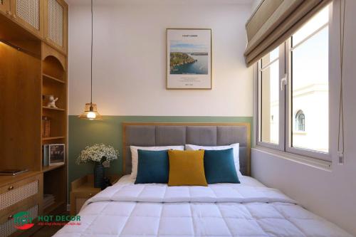 a bedroom with a bed with blue and yellow pillows at Hoàng Gia villa Novaworld in Bình Sum