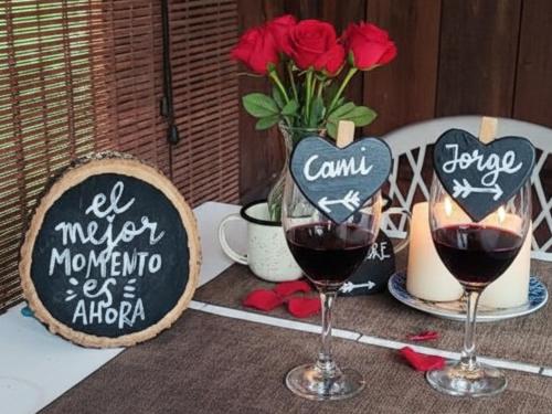 a table with two glasses of wine and a vase of roses at El Color de Mis Rêves in Villamaría