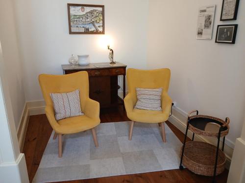 two yellow chairs sitting next to a desk with a pillow at AL Marias de Órion in Coimbra