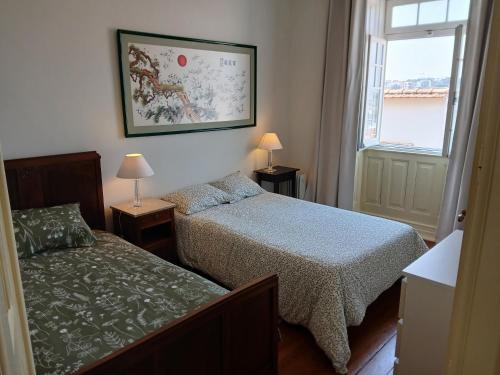 a bedroom with two beds and a window at AL Marias de Órion in Coimbra
