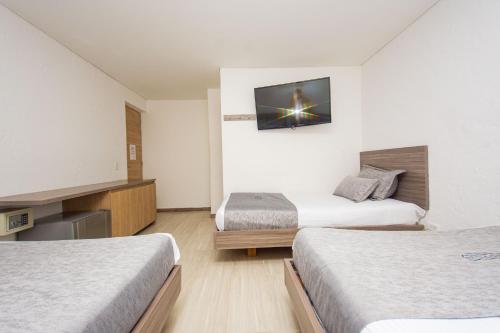 a hotel room with two beds and a tv on the wall at Novus Laureles in Medellín