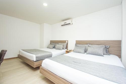 a bedroom with two beds and a chair in it at Novus Laureles in Medellín