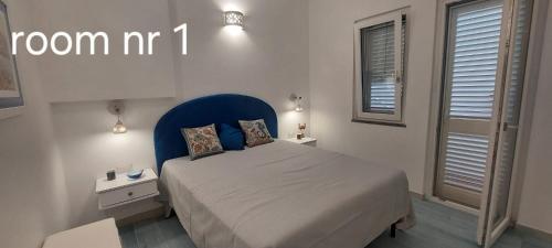 a bedroom with a bed with a blue headboard and windows at Cielo e Mare in Positano