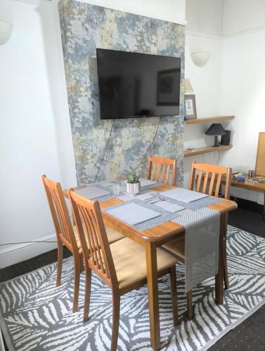 a dining room table with chairs and a television on a wall at City Vacations Kettering free WiFi for ' Short & Long stays ' Shared bathroom & Shared Kitchen Single room for 1 Adult in Kettering