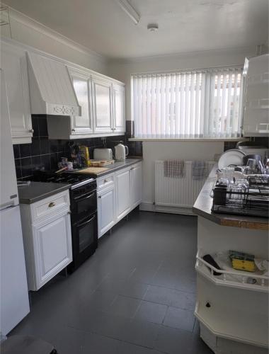 a white kitchen with white cabinets and black appliances at City Vacations Kettering free WiFi for ' Short & Long stays ' Shared bathroom & Shared Kitchen Single room for 1 Adult in Kettering