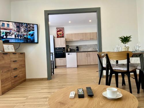 a living room with a table and a kitchen at L indémodable rénové spacieux et lumineux avec 2 chambres in Sarrebourg