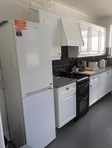 a kitchen with white cabinets and a white refrigerator at City Vacations Kettering free WiFi for ' Short & Long stays ' Shared bathroom & Shared Kitchen Single room for 1 Adult in Kettering