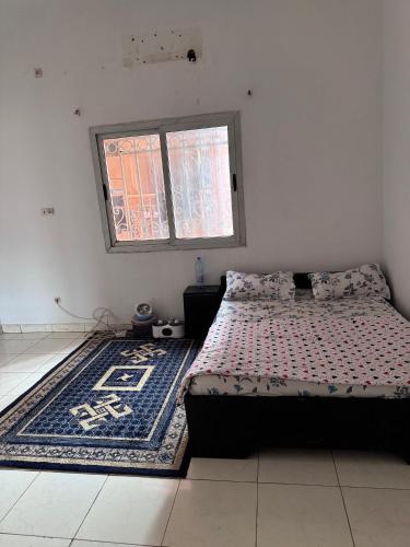 a bedroom with a bed and a rug and a window at Mandé Habitat in Bamako
