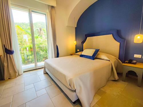 a bedroom with a bed and a large window at Hotel La Pergola in Santa Maria di Castellabate