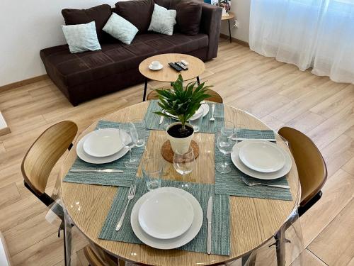 a dining room table with plates and a plant on it at L indémodable rénové spacieux et lumineux avec 2 chambres in Sarrebourg