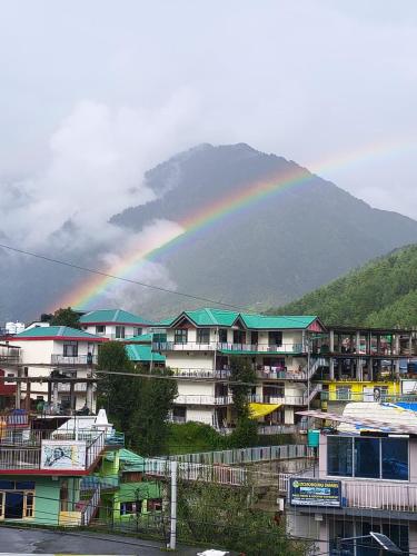 a rainbow over a group of buildings with a mountain at Aliza Inn And Suites By SRS Hotels in Dharamshala