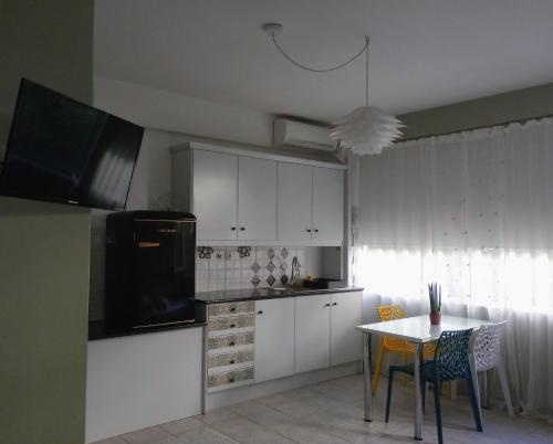 a kitchen with white cabinets and a small table and a table and a tableearcher at Daisy in Nafplio
