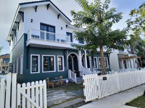 a blue and white house with a white fence at Hoàng Gia villa Novaworld in Bình Sum