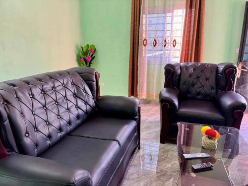 a living room with a leather couch and two chairs at Charming apartment in Yaoundé - Nkolmesseng in Yaoundé