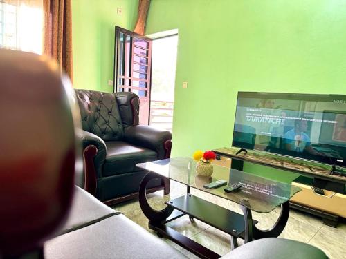 a living room with a television and a couch and a table at Charming apartment in Yaoundé - Nkolmesseng in Yaoundé