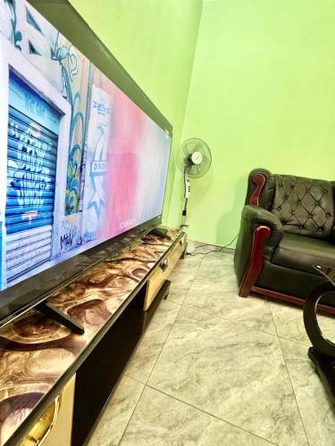 a living room with a large screen tv and a chair at Charming apartment in Yaoundé - Nkolmesseng in Yaoundé